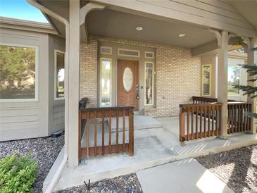 Covered front porch with brick facade and detailed wood features at 7292 Firethorn, Littleton, CO 80125