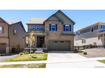 Charming two-story home features a stone facade, attached garage, and well-manicured lawn at 1632 Saddlesmith Pl, Castle Pines, CO 80108