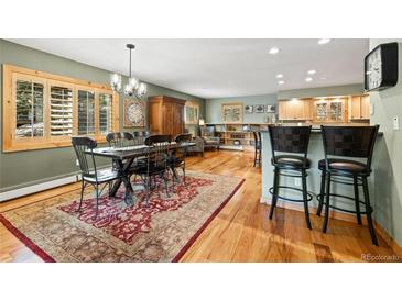 Open-concept dining area featuring a rustic table, ornate rug, and bar seating adjacent to the living area at 100 River Park Dr # A, Breckenridge, CO 80424