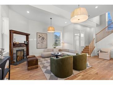 Bright living room with a decorative fireplace, modern lighting, and wood staircase at 817 29Th St, Denver, CO 80205