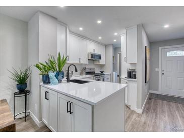 Well-lit kitchen with white cabinets, stainless appliances, and an island with a black faucet at 1811 S Quebec Way # 103, Denver, CO 80231