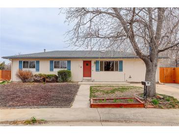 Charming single-story home featuring a well-maintained front yard, trimmed bushes, and a vibrant red front door at 1056 S Macon Way, Aurora, CO 80012