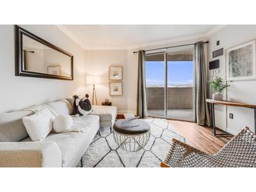 Bright living room featuring a white sofa, modern rug, and sliding glass doors to a balcony at 601 W 11Th Ave # 1101, Denver, CO 80204