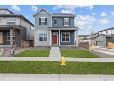 Charming two-story home with a red door, landscaped yard, and concrete walkway, with a fire hydrant in the front yard at 21202 E 63Rd Dr, Aurora, CO 80019