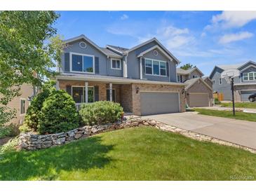 Charming two-story home with brick and siding, a well-manicured lawn, and a two-car garage at 14185 W Warren Cir, Lakewood, CO 80228