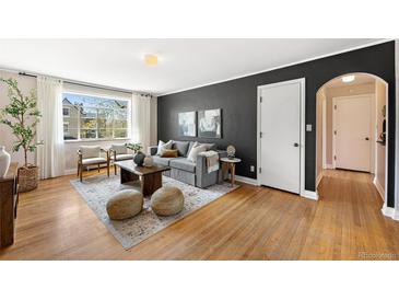 Inviting living room features hardwood floors, a cozy gray sofa, and ample natural light from a large window at 1321 E 10Th Ave # 4, Denver, CO 80218