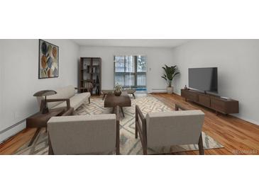 Bright living room features hardwood floors, a sliding door to the balcony, and stylish furnishings at 6930 E Girard Ave # 106, Denver, CO 80224