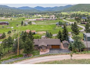 Charming home with a spacious yard surrounded by lush greenery and mountain views at 24030 San Isabel Rd, Indian Hills, CO 80454