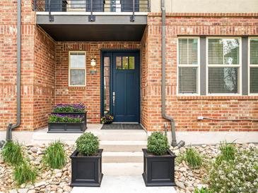 Charming brick home featuring a striking blue front door, rock garden, and elegant potted plants at 181 S Monaco Pkwy, Denver, CO 80224