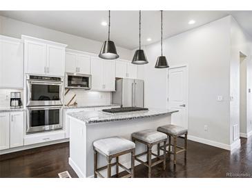 Bright kitchen features stainless appliances, granite counters, and a central island with barstool seating at 181 S Monaco Pkwy, Denver, CO 80224