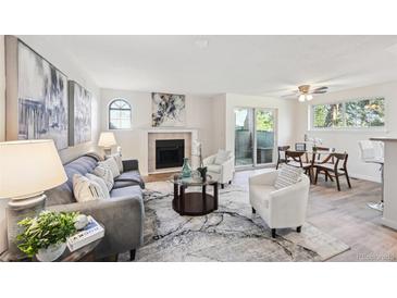 Bright living room features a fireplace, neutral walls, sleek flooring, and a sliding glass door to a balcony at 7680 Depew St # 1404, Arvada, CO 80003