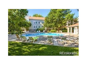 Relaxing community pool surrounded by mature trees and lounge chairs at 7680 Depew St # 1404, Arvada, CO 80003