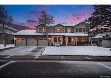 Charming two-story home boasting a three-car garage and attractive brick accents, all beneath a colorful twilight sky at 11418 W Roxbury Ave, Littleton, CO 80127