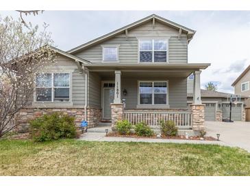 Charming two-story home with a cozy front porch, stone accents and a well-maintained lawn at 11801 E 118Th Ave, Commerce City, CO 80640