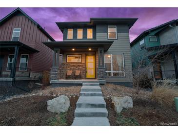 Modern two-story home with a yellow front door, stone accents, and landscaped front yard at 6052 N Malta St, Aurora, CO 80019