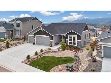 Charming gray home with a three car garage and beautifully xeriscaped front yard at 16840 New Autumn Dr, Monument, CO 80132