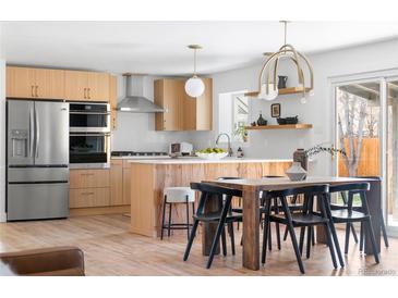 Bright kitchen features stainless appliances, modern cabinets, and center island with seating and adjacent dining area at 417 S Pontiac Way, Denver, CO 80210