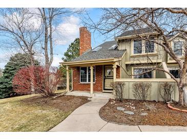 Charming townhouse with brick chimney, covered entryway, and established landscaping at 7765 S Curtice Dr # A, Littleton, CO 80120