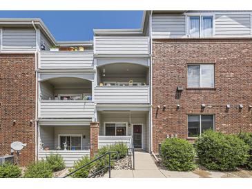 Multi-level condo building with brick and siding and multiple balconies and a red front door at 5537 Lewis Ct # 4, Arvada, CO 80002