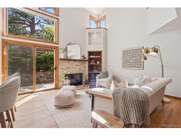 Bright living room with stone fireplace, hardwood floors, and large windows offering natural light at 31402 N Bermuda Dunes Dr, Evergreen, CO 80439