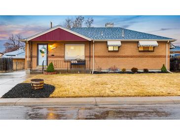 Charming brick home with a well-manicured lawn, red awning, and blue roof at 7131 Raritan St, Denver, CO 80221