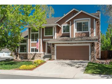 Charming two-story home featuring a stone-accented facade, two-car garage, and a well-maintained front yard with mature trees at 19099 E Creekside Dr, Parker, CO 80134