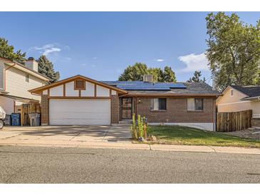 Cozy brick home featuring solar panels, an attached garage, and a well-maintained front yard at 17675 E Girard Ave, Aurora, CO 80013