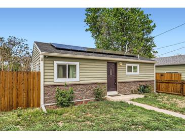 Charming single-story home with solar panels, stone accents, and well-maintained front yard at 7101 E 66Th Ave, Commerce City, CO 80022