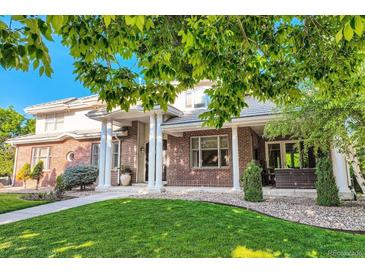 Gorgeous brick home with elegant columns, a well-manicured lawn, and lush landscaping at 6790 W Crestline Ave, Littleton, CO 80123
