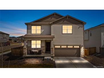 Charming two-story home featuring a covered front porch with stone accents and a two-car garage at 9248 Salida St, Commerce City, CO 80022
