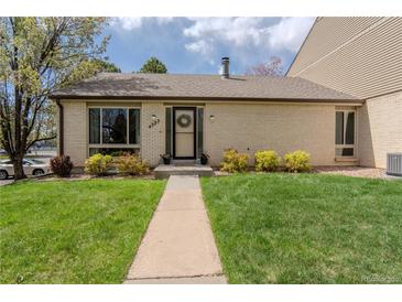 Charming brick home featuring a well-manicured lawn and inviting front entryway with a wreath on the front door at 4323 W Ponds Cir, Littleton, CO 80123