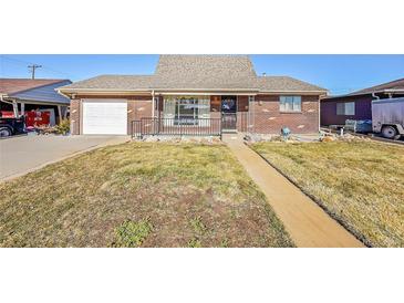 Brick ranch house with attached garage and landscaped yard at 5621 Demott Ave, Commerce City, CO 80022