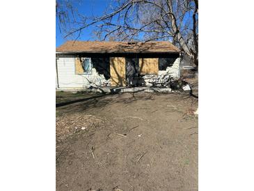 Damaged home with boarded windows and debris in the yard at 1165 S Winona Ct, Denver, CO 80219