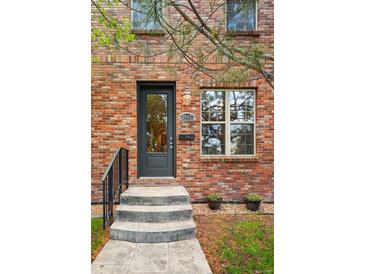 Charming brick home featuring a modern black front door, stone steps, and a beautifully landscaped yard at 3482 E 28Th Ave, Denver, CO 80205