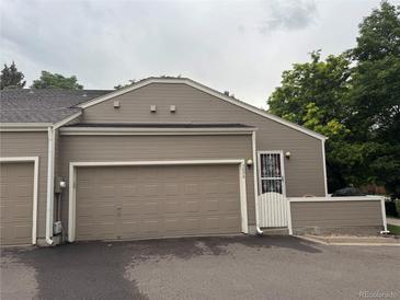 Beige home featuring a two-car garage and a charming entrance with a security door at 5898 W Asbury Pl, Lakewood, CO 80227