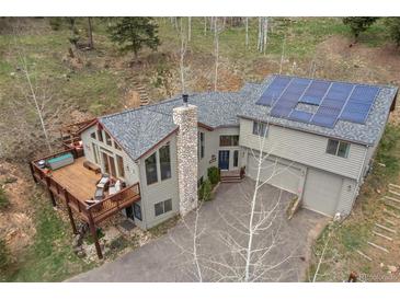 Stunning mountain home featuring solar panels, stone chimney, and a large deck perfect for outdoor living at 32209 Blue Springs Dr, Evergreen, CO 80439