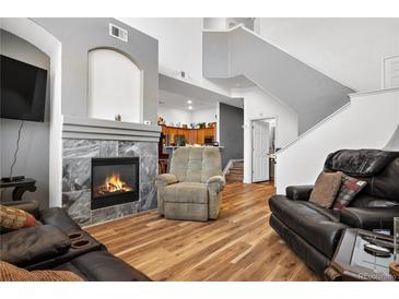 Inviting living room featuring a cozy fireplace, hardwood floors and plush seating at 8944 Fox Dr, Denver, CO 80260