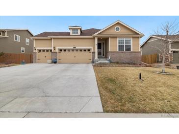 Charming tan home featuring a three-car garage and well-maintained front yard at 16034 Columbine St, Thornton, CO 80602