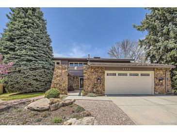 Charming home featuring stone accents, a two-car garage, a well-maintained lawn and beautiful landscaping at 6922 W Walden Pl, Littleton, CO 80128