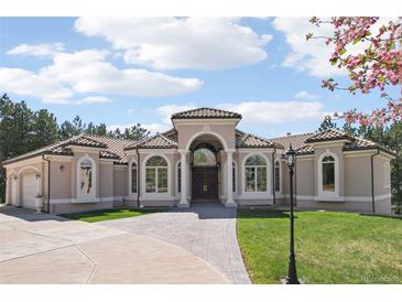 Stunning home with arched windows, portico, and tile roof situated on a large lot at 6180 E Quincy Ave, Cherry Hills Village, CO 80111