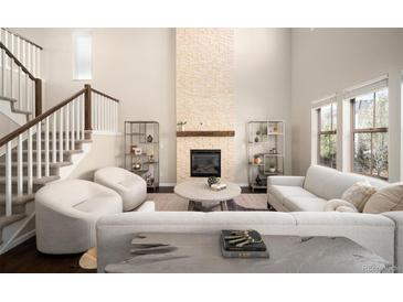 Open-concept living room boasts a floor-to-ceiling fireplace, stairs, and lots of natural light at 2559 S Kendrick St, Lakewood, CO 80228