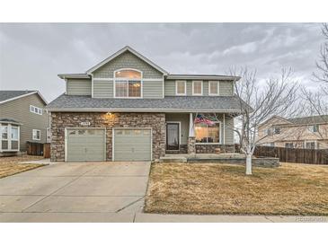 Charming two-story home with stone accents, attached two-car garage, landscaped front yard, and covered front porch at 1793 E 164Th Pl, Brighton, CO 80602