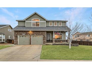 Charming two-story home featuring a stone facade, well-manicured lawn, and an attached two-car garage at 1793 E 164Th Pl, Thornton, CO 80602