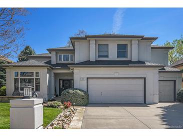 Charming two-story stucco home featuring a manicured lawn and an attached two-car garage at 3002 S Oak Way, Lakewood, CO 80227