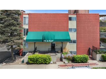 The condo building entrance features a green awning with well maintained landscape elements at 200 N Pearl St # 106, Denver, CO 80203