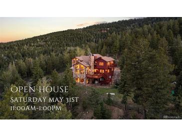 Stunning mountain home with rustic stone and wood exterior, surrounded by lush forest at dusk at 30717 Conifer Mountain Dr, Conifer, CO 80433
