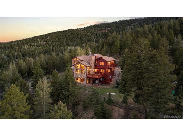An inviting two-story home nestled in the trees with stone and red siding and wooden decks at 30717 Conifer Mountain Dr, Conifer, CO 80433