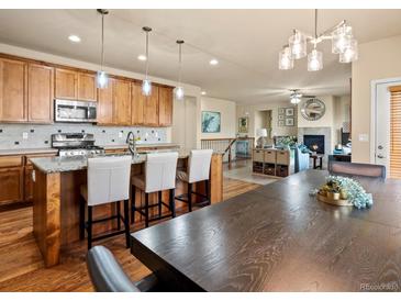 Open kitchen and living room space with granite counters, hardwood floors, and stainless steel appliances at 1907 Windemere Ln, Erie, CO 80516