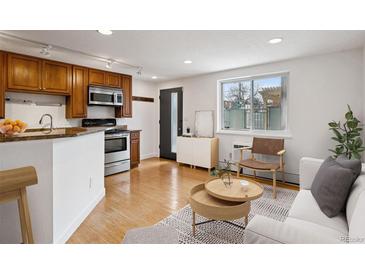 Cozy living area with open kitchen, featuring stainless steel appliances and natural light from a large window at 1 N Pearl St # 102, Denver, CO 80203