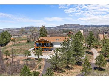 Charming home featuring a spacious deck, set against a backdrop of rolling hills and a bright, open sky at 3303 Wolfensberger Rd, Sedalia, CO 80135